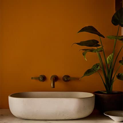 Modernes Badezimmer mit Wänden in Ashes of Marigold. Das warme, erdige Orange bildet einen spannenden Kontrast zum Waschtisch in Perpetual Blue und dunklen Details in Vulcan.